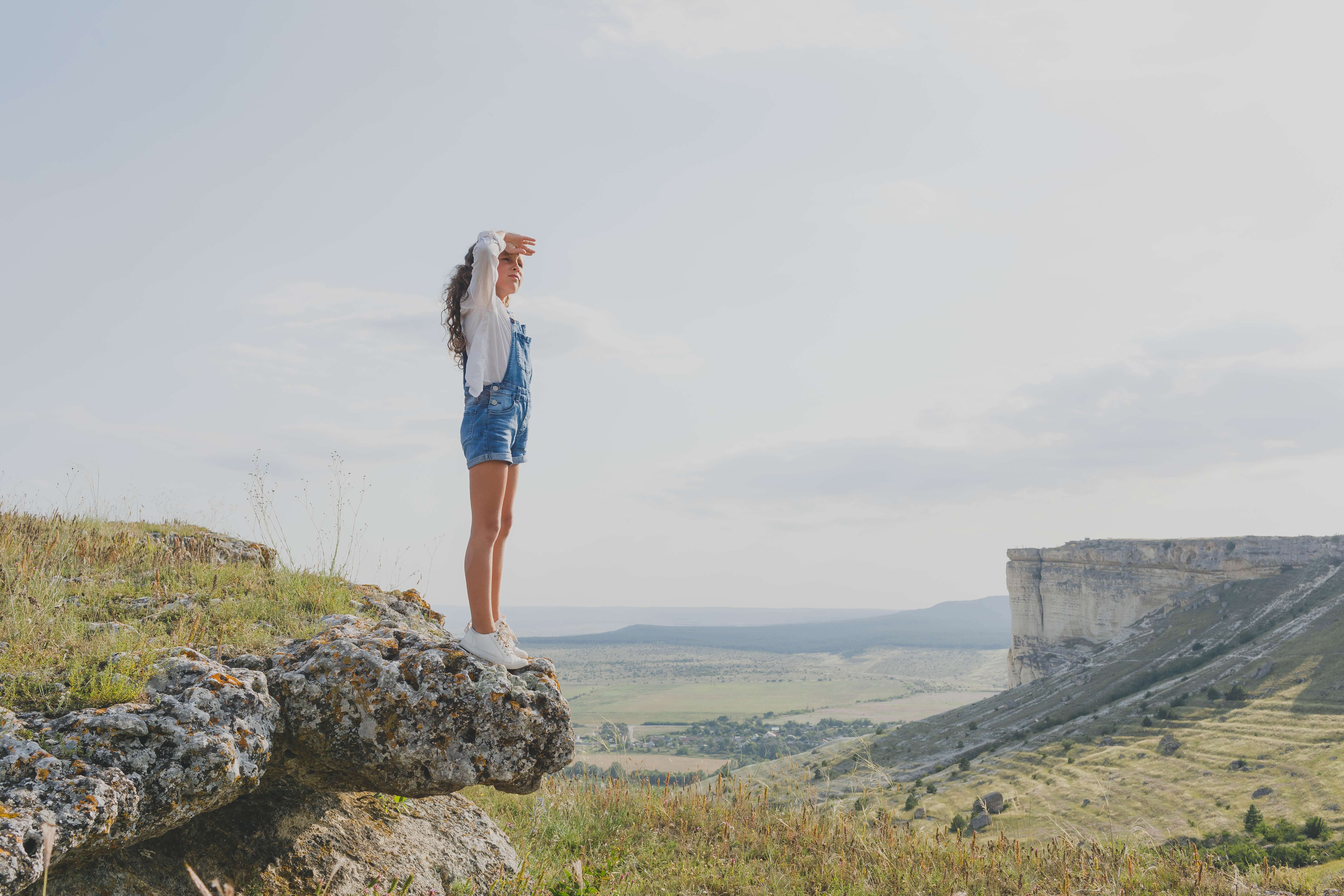 the-girl-stands-on-the-mountain-and-looks-ahead-Web